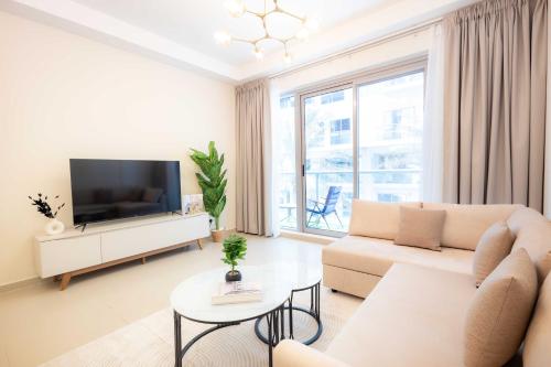 a living room with a couch and a tv at Modern 1BR with Beach and Pool in Al Marjan Island in Ras al Khaimah