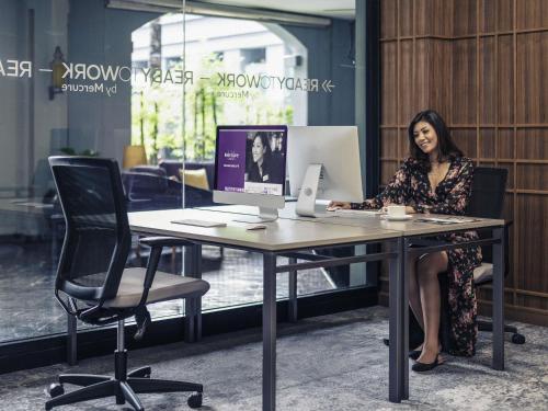 a woman sitting at a desk with a computer at Mercure Yangon Kaba Aye in Yangon