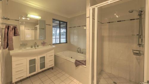 a bathroom with a tub and a sink and a shower at Sommerville Valley Tourist Park & Resort in Stanthorpe
