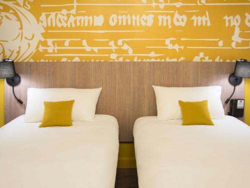 two beds sitting next to each other in a room at ibis Styles Carcassonne La Cité in Carcassonne