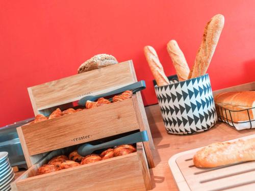 a table with two wooden boxes filled with bread at ibis Styles Carcassonne La Cité in Carcassonne