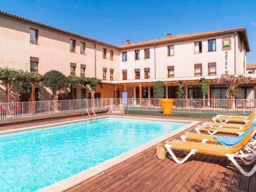 a swimming pool with two lounge chairs and a building at ibis Styles Carcassonne La Cité in Carcassonne