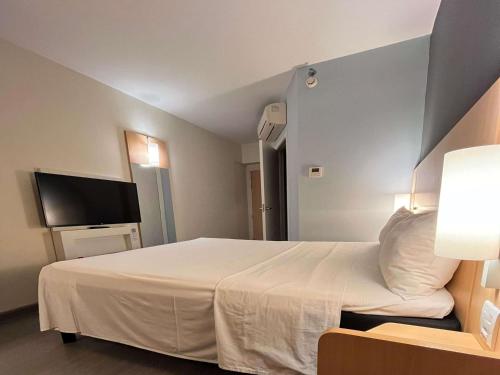 a hotel room with a bed and a flat screen tv at ibis Catalao in Catalão