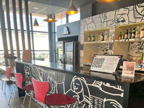 a bar with pink chairs and a laptop on a counter at ibis Catalao in Catalão