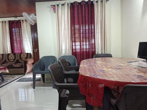 a room with a table and chairs and a couch at Fortune Holiday cottage in Madikeri