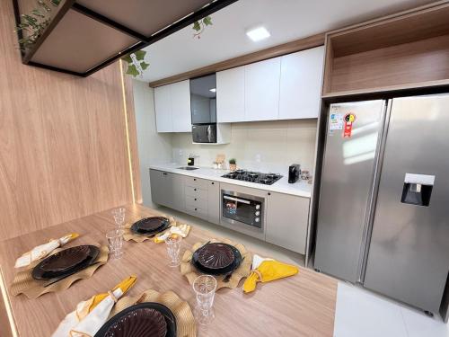a kitchen with a table and a stainless steel refrigerator at Feel Home Duplex no Bessa com Jacuzzi Privativa in João Pessoa