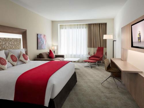 a hotel room with a large bed and a living room at Novotel Jeddah Tahlia in Jeddah