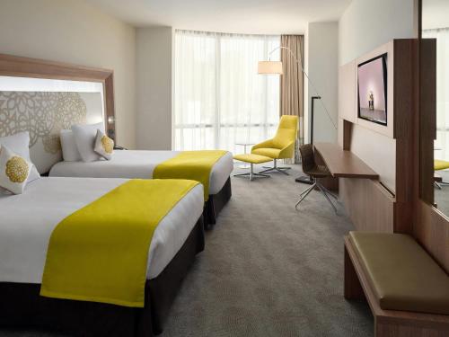 a hotel room with two beds and a television at Novotel Jeddah Tahlia in Jeddah