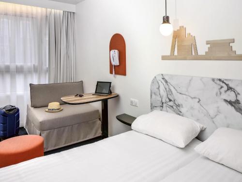 a room with two beds and a desk with a laptop at Hôtel ibis Styles Vichy Centre in Vichy