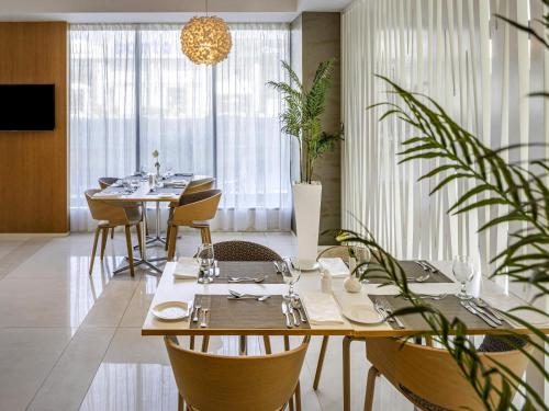 a dining room with tables and chairs and plants at Novotel Jeddah Tahlia in Jeddah