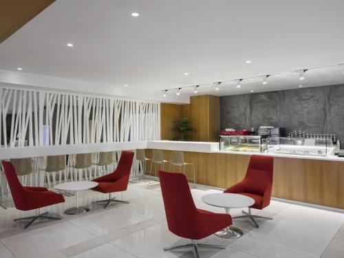 a restaurant with red chairs and a counter at Novotel Jeddah Tahlia in Jeddah