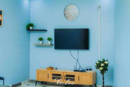 ein Wohnzimmer mit einem Fernseher an einer blauen Wand in der Unterkunft B First Complex in Kolwezi