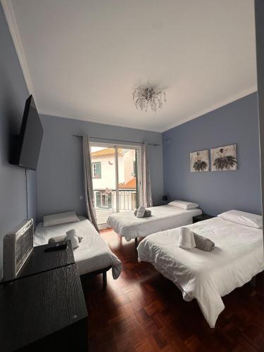 a bedroom with two beds and a television and a window at VILLA Valhalla Private heated swimming-pool in Funchal