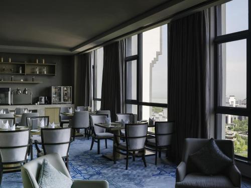a restaurant with tables and chairs and large windows at Pullman Hefei Sunac in Hefei