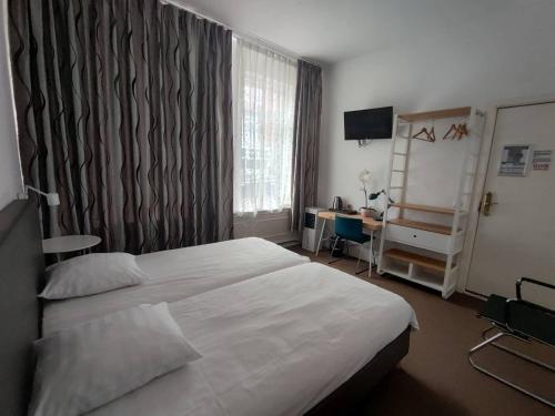 a hotel room with a bed and a desk at New City Hotel Scheveningen in Scheveningen