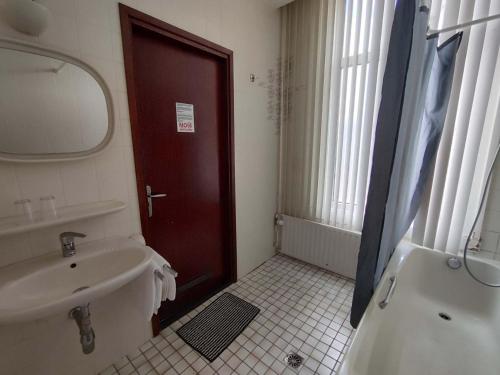 a bathroom with a sink and a mirror and a door at New City Hotel Scheveningen in Scheveningen