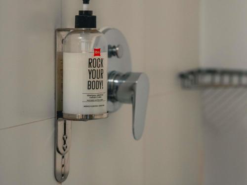 a bottle of soap is hanging on a wall in a bathroom at ibis Lima Reducto Miraflores in Lima