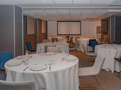 a conference room with white tables and chairs and a screen at ibis Lima Reducto Miraflores in Lima