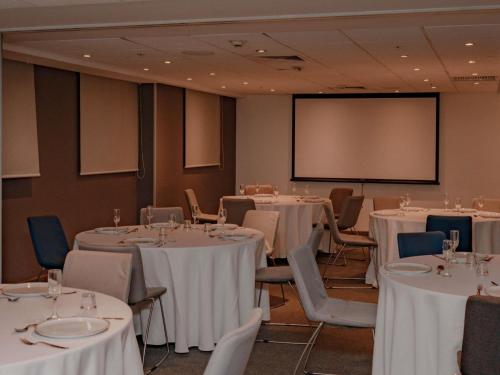 a conference room with white tables and chairs and a screen at ibis Lima Reducto Miraflores in Lima