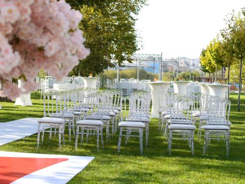 a row of white chairs in a field with pink flowers at Ibis Istanbul Tuzla Hotel in Tuzla