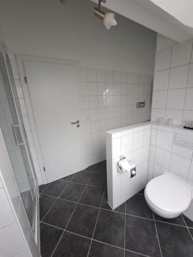 a white bathroom with a toilet and a shower at Hotel Rosengarten in Bad Salzuflen