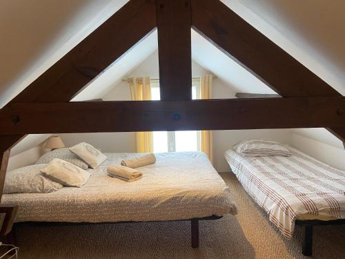 una camera da letto con due letti in mansarda di Le Cottage Normand ad Annebault