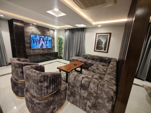 a living room with a couch and chairs and a tv at Gold Crest Mall & Residency Premium Apartments With Al-Fatah Store & Shopping Mall in Lahore