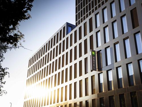 a tall building with the sun shining on it at ibis Styles Basel City in Basel