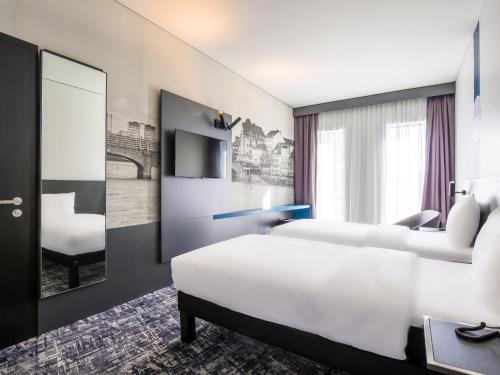 a hotel room with two beds and a tv at ibis Styles Basel City in Basel
