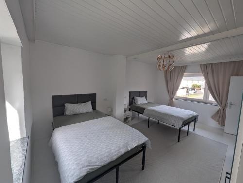 a white bedroom with two beds and a window at Haus Haiderbach Nähe A3 in Wittgert
