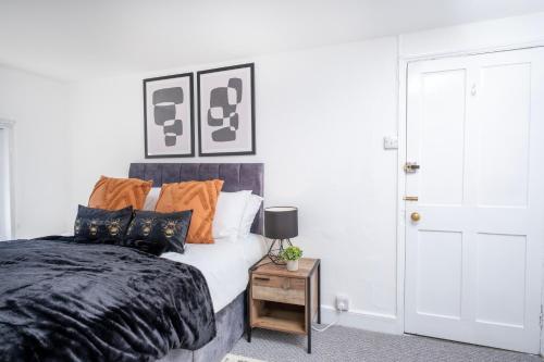 a bedroom with a bed with orange and black pillows at Gloucester Street Nest - 3BR Flat for 6 Guests in Stroud