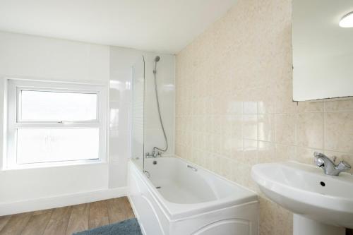 a white bathroom with a sink and a bath tub at Gloucester Street Nest - 3BR Flat for 6 Guests in Stroud