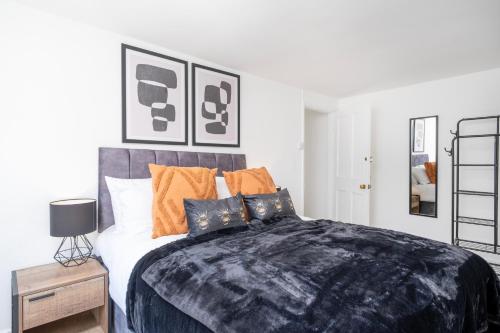 a bedroom with a large bed with orange and blue pillows at Gloucester Street Nest - 3BR Flat for 6 Guests in Stroud