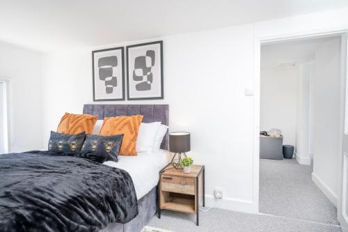 a bedroom with a bed with orange and black pillows at Gloucester Street Nest - 3BR Flat for 6 Guests in Stroud