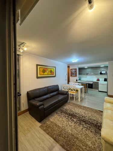 a living room with a leather couch and a table at Arriendo dos dormitorios Costas in Concón