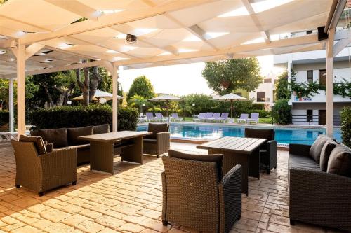 a patio with tables and chairs and a pool at Terinikos Sunny Garden Hotel & Junior Suites New Renovation 2025 in Ialyssos