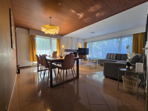 a living room with a table and chairs and a couch at Charmante villa avec terrasse et jardin arboré in Geneva
