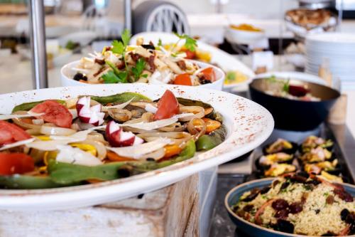 a buffet with plates of food on a table at Holiday Inn Mauritius Mon Trésor by IHG in Blue Bay