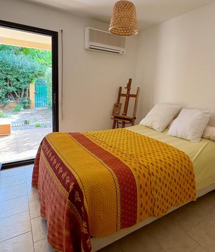 a bedroom with a bed with a yellow and red blanket at La cigale bleue - Garden level in Sanary-sur-Mer