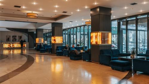 a lobby with couches and chairs and windows at Grand Hotel Napoca in Cluj-Napoca