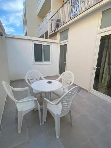 a white table and chairs on a patio at Ghadira Bay Retreat by MA Properties in Is-Sellum