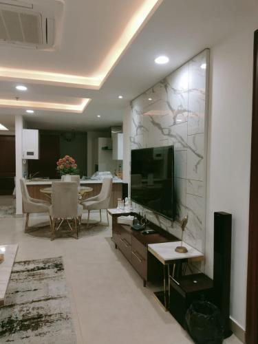 a living room with a television and a dining room at Gold Crest Mall & Residency Premium Apartments With Al-Fatah Store & Shopping Mall in Lahore