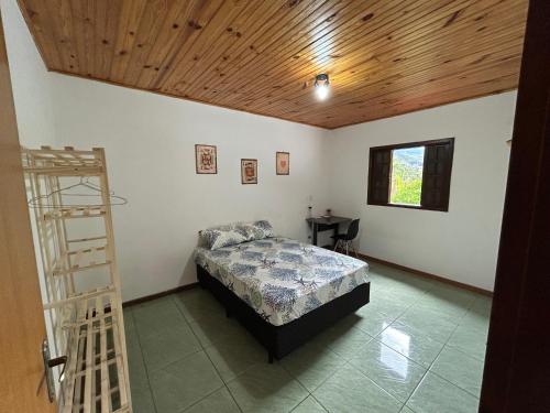 une chambre avec un lit et un plafond en bois dans l'établissement Casa Paiol Grande, à São Bento do Sapucaí