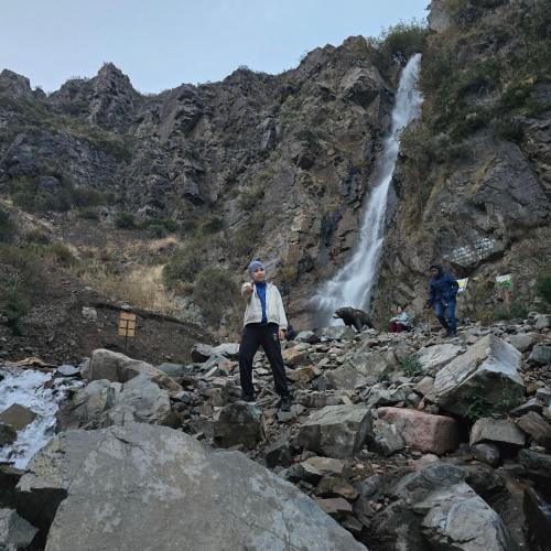 Un uomo che si trova su rocce di fronte a una cascata di Turgen resort a Türgen