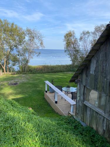 a wooden house with a bench and a table and the ocean at The Fishermans Net House in Bigauņciems