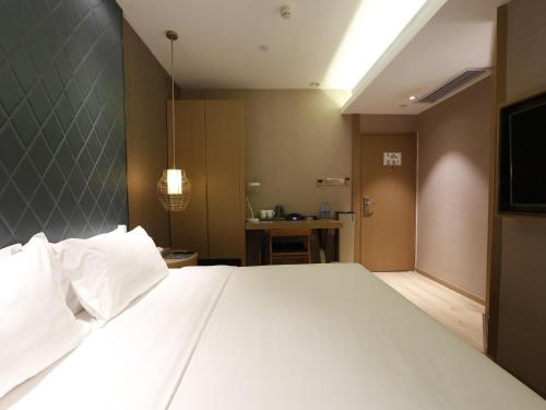 a bedroom with a large white bed and a television at Ibis Styles XM Zhongshan Hotel in Xiamen