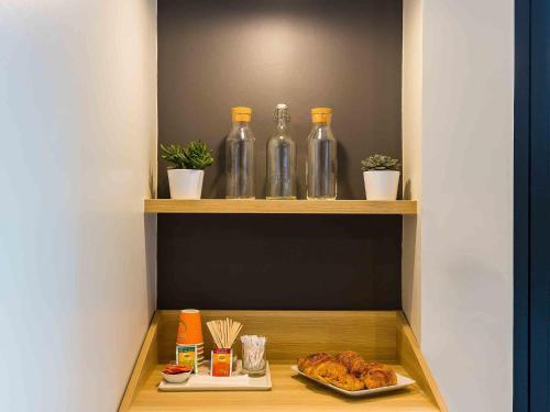 a shelf with bottles and a plate of food at Ibis Styles Paris Place d'Italie - Butte Aux Cailles in Paris