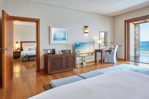 ein Hotelzimmer mit einem Bett und einem Schreibtisch und einem Schlafzimmer in der Unterkunft Grand Resort Lagonissi in Lagonisi