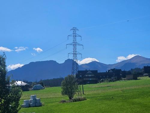 a electricity pole in a field with mountains in the background at Highland Apartments Pod Gubałówką in Zakopane