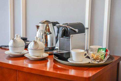 a table with cups and a coffee maker on it at Grand Hotel Napoca in Cluj-Napoca